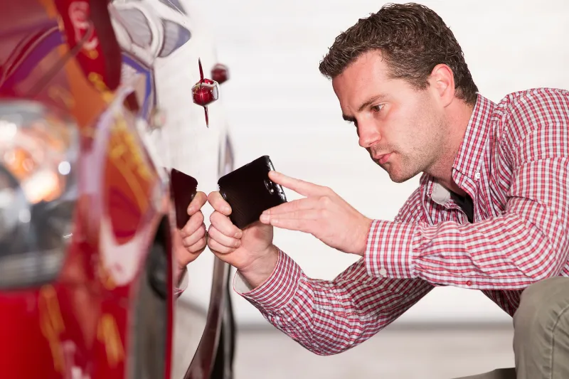 Ajustador revisando los daños materiales de un auto tras un choque