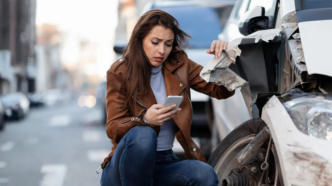 Mujer revisando su teléfono después de un accidente