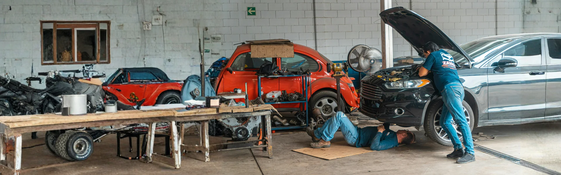 Mecánicos reparan autos dentro de un taller