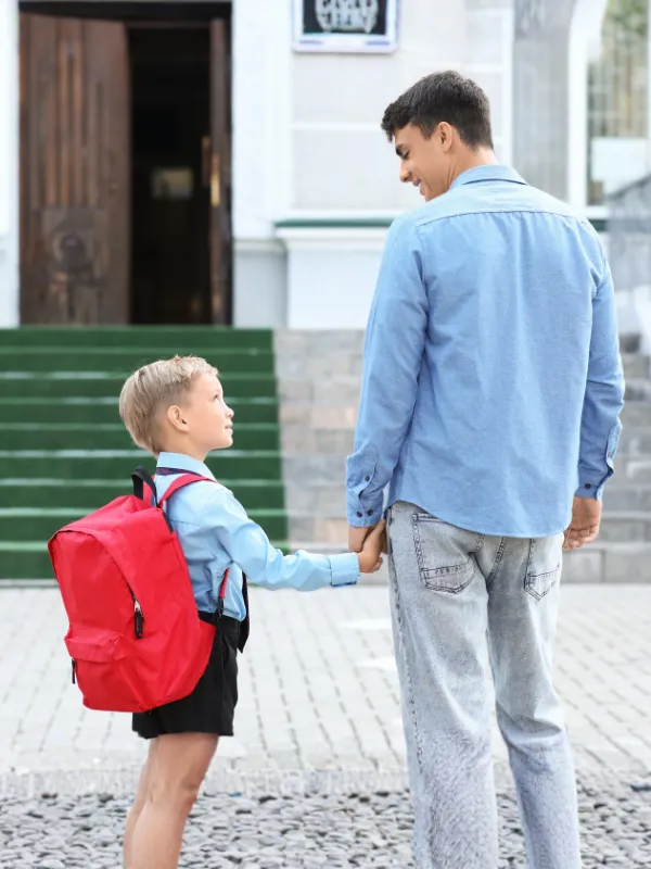 Padre llevando de la mano a su hijo con mochila camino a la escuela