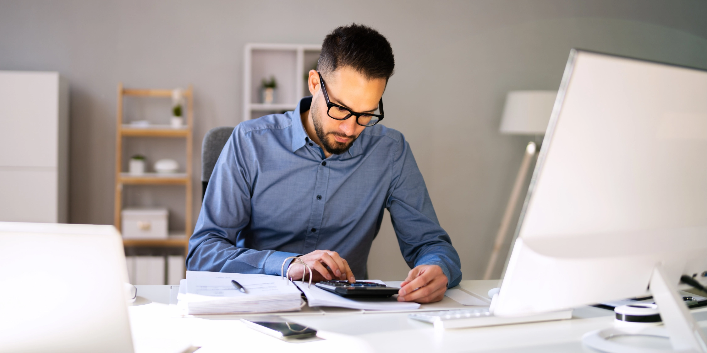 Contador revisando cuentas con calculadora en su escritorio