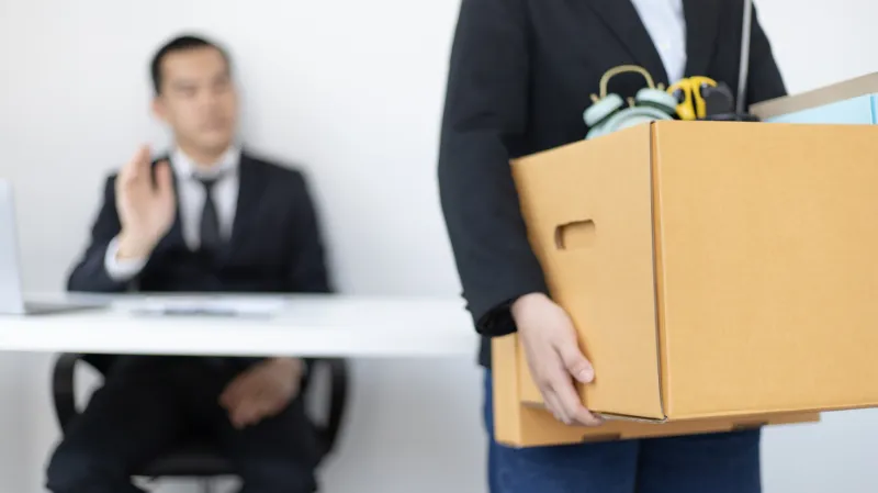 Joven dejando su empleo con sus cosas en una caja