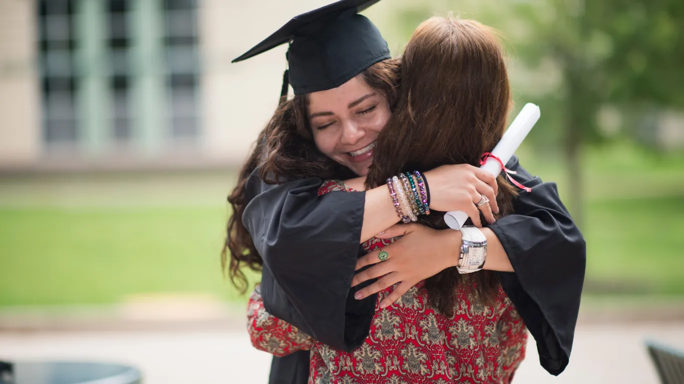 Madre abrazando a su hija el día de su graduación universitaria