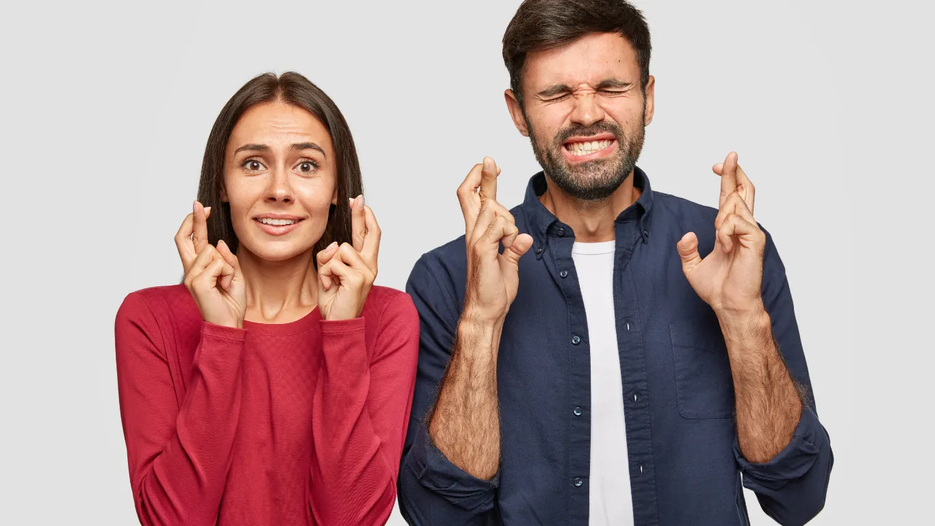 Pareja con los dedos cruzados y gesto de preocupación: la etapa de la pregunta incómoda, ¿me alcanzará para retirarme?